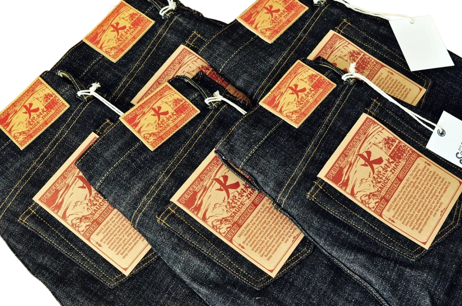 Dark indigo fire selvedge tapered raw denim jeans with orange and brown woven labels featuring a red cross design