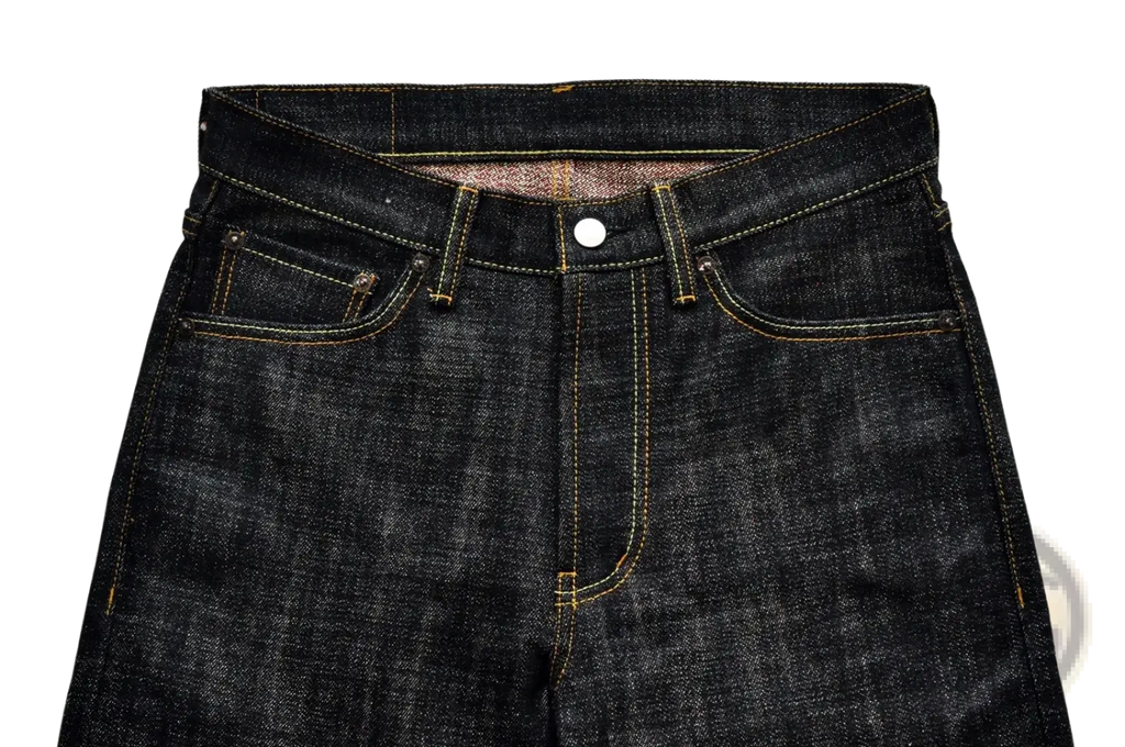 Dark indigo Saucezhan Fire Selvedge tapered raw denim jeans with yellow stitching and white button closure