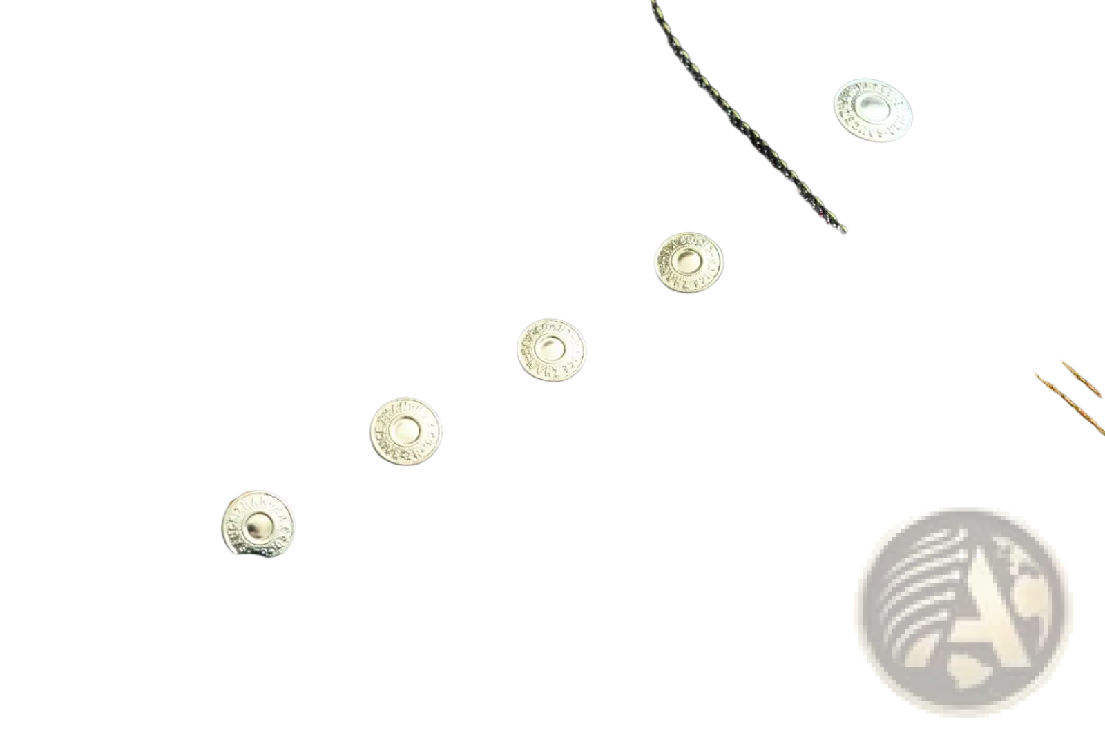 Silver-toned metal buttons with a raised design on dark indigo denim of saucezhan fire selvedge tapered raw jeans