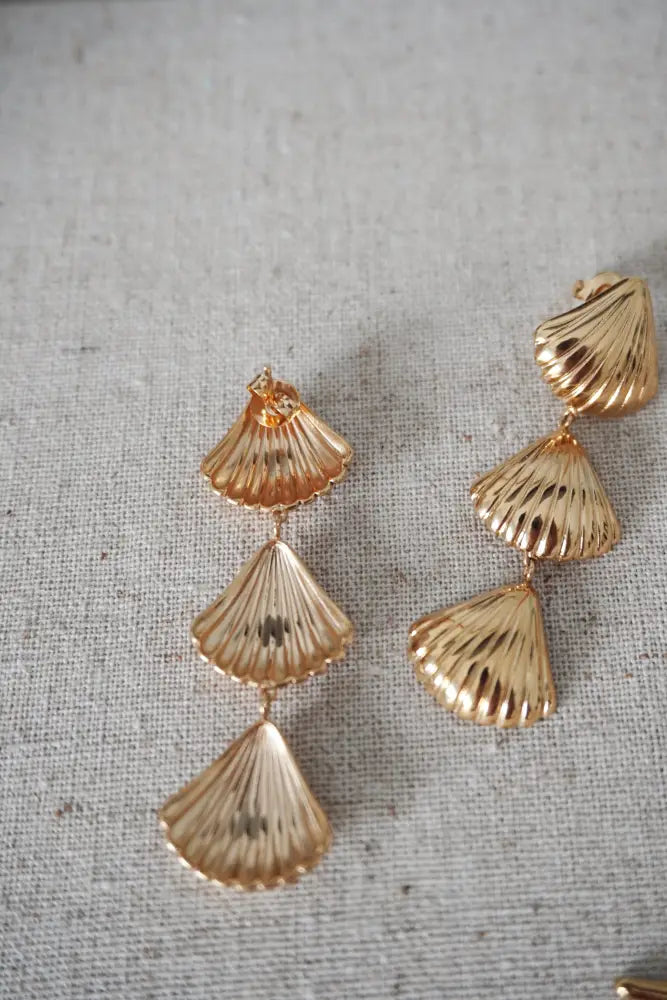 Gold layered scallop shell drop earrings feature a gold-toned, fan-like layered design with subtle ridged texture