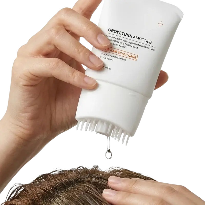 White tube of grow turn scalp treatment serum with built-in bristle brush and droplet falling from the tip