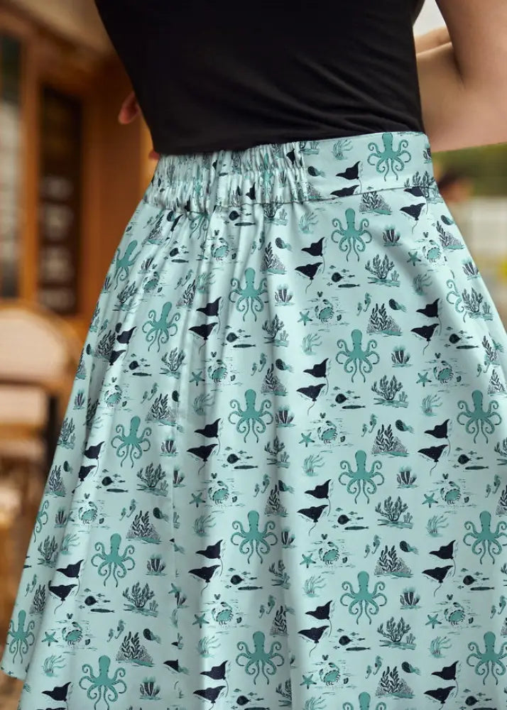 A light blue cotton sea skater a-line skirt with a playful nautical print of teal and black octopuses and marine plants