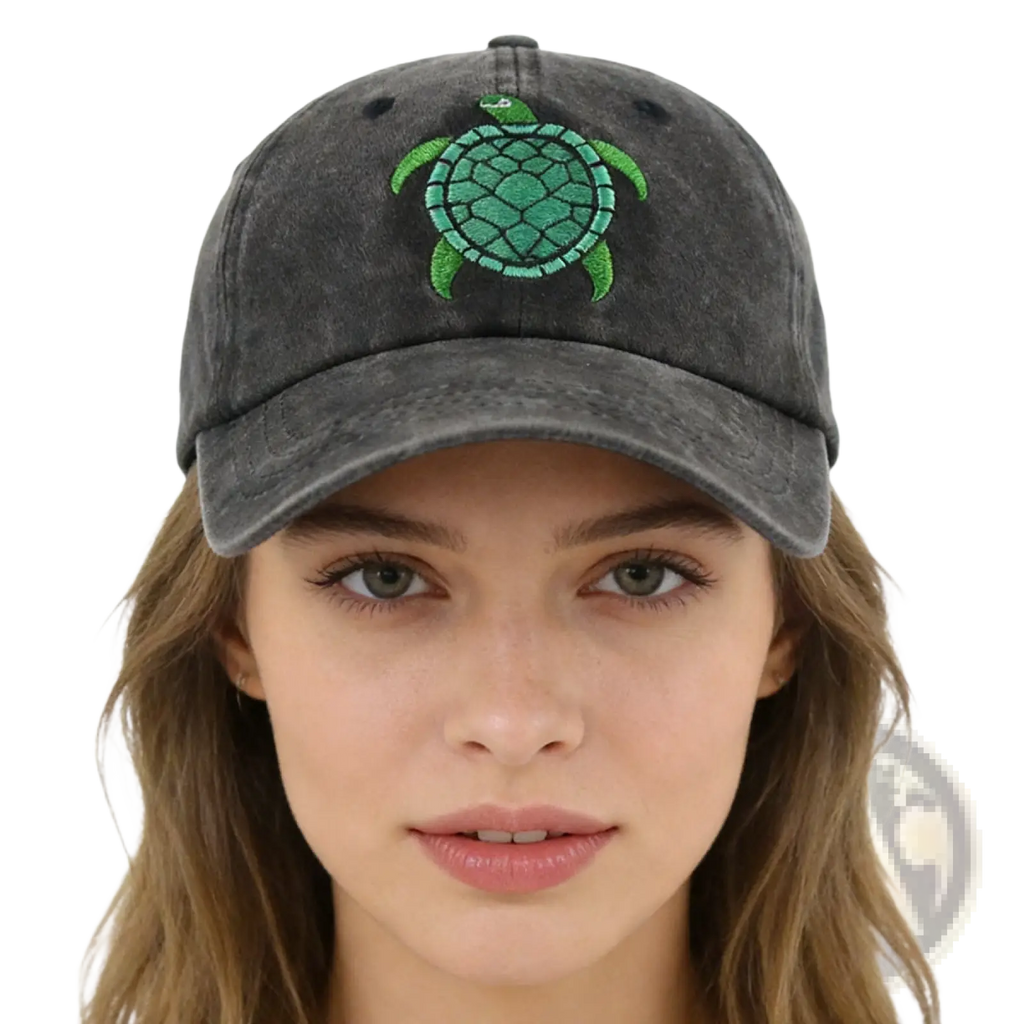 A dark gray distressed baseball cap with a vibrant green embroidered sea turtle design on the front