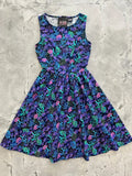 A sleeveless sea vintage neon tropical cotton a-line dress in vibrant purple and teal with pink floral pattern