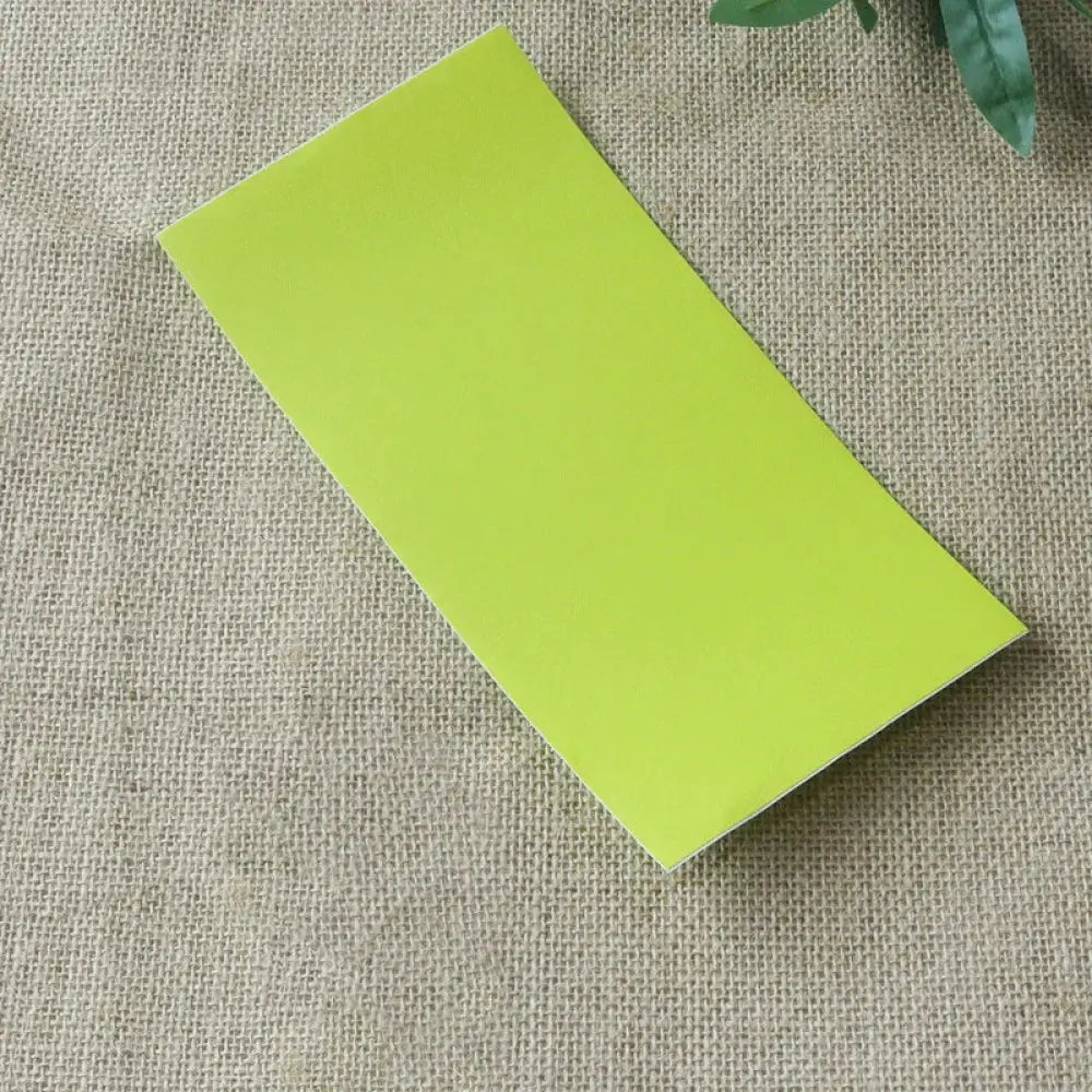 A sleek lime-green rectangular sticky note pad with a smooth matte finish shown alongside navy blue leather sofa repair patch