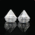 Two clear faceted diamond-shaped acrylic refillable travel cosmetic bottles with textured bases