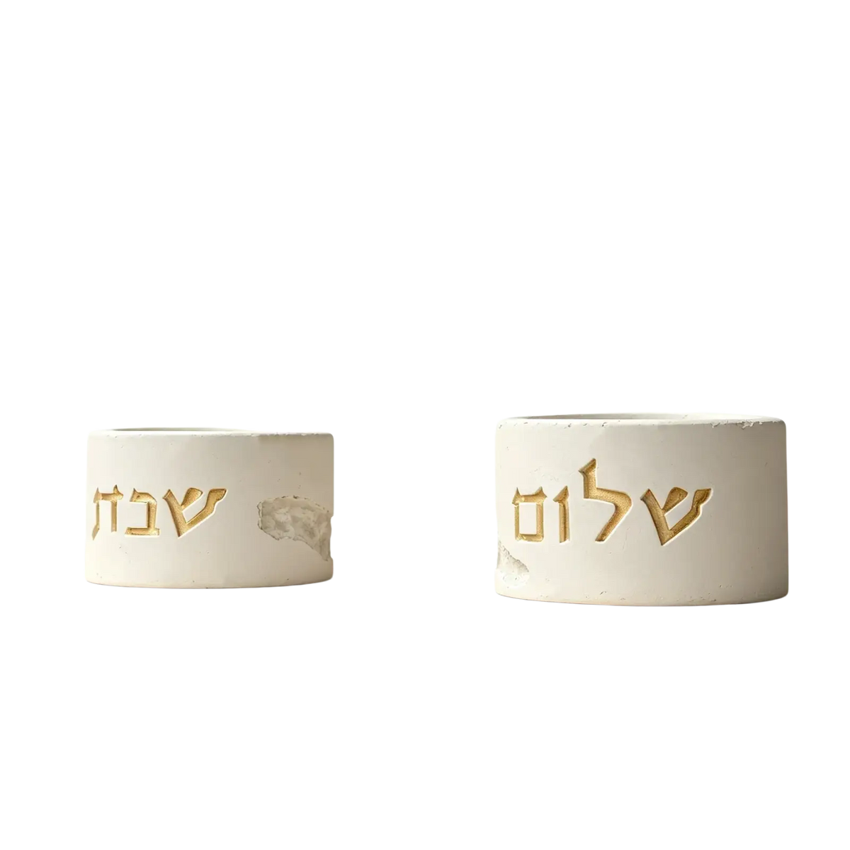 Two white concrete shabbat candle holders with gold hebrew lettering made from silicone mold material