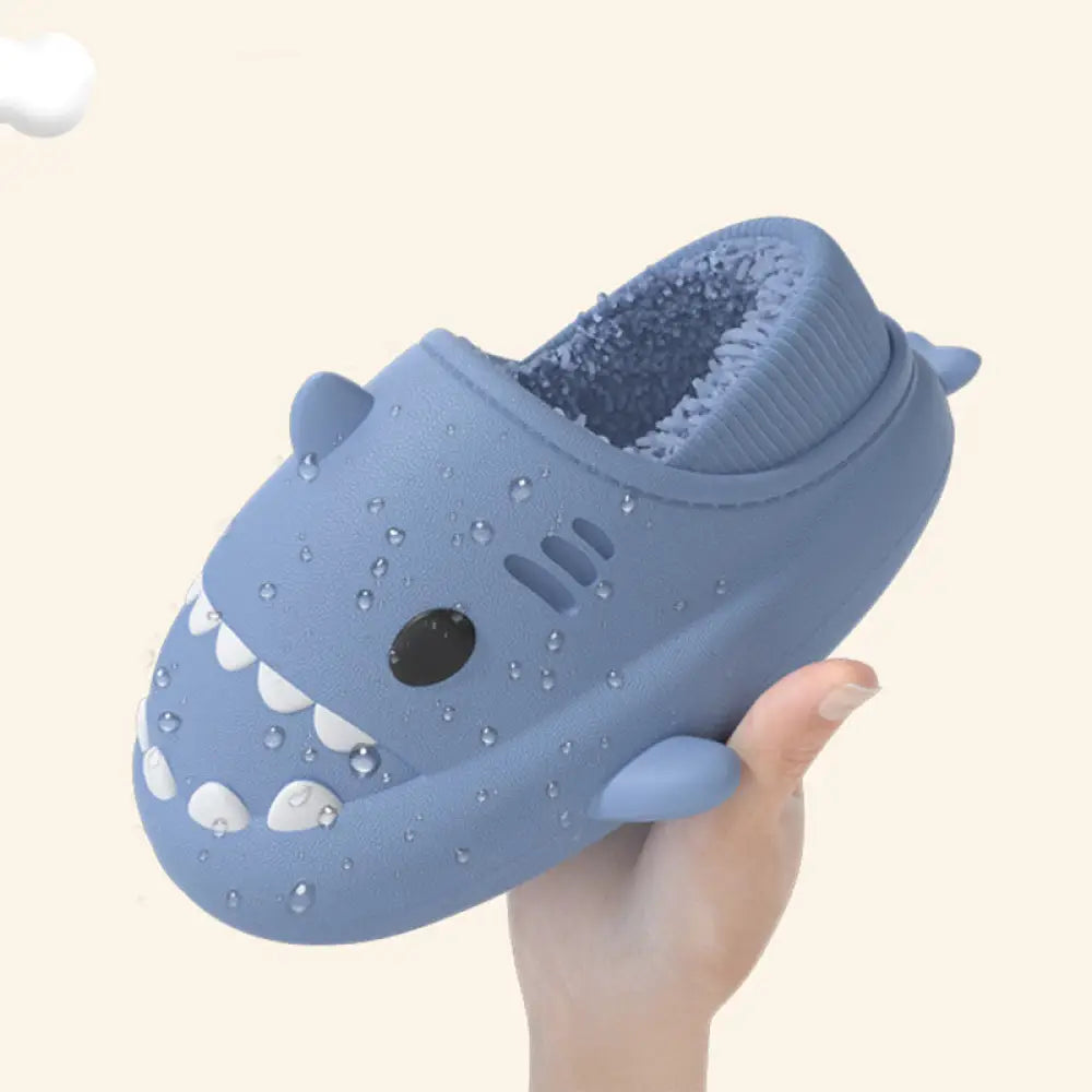 Plush shark winter house slipper in blue with white teeth and black eye made of soft rubber soles and material