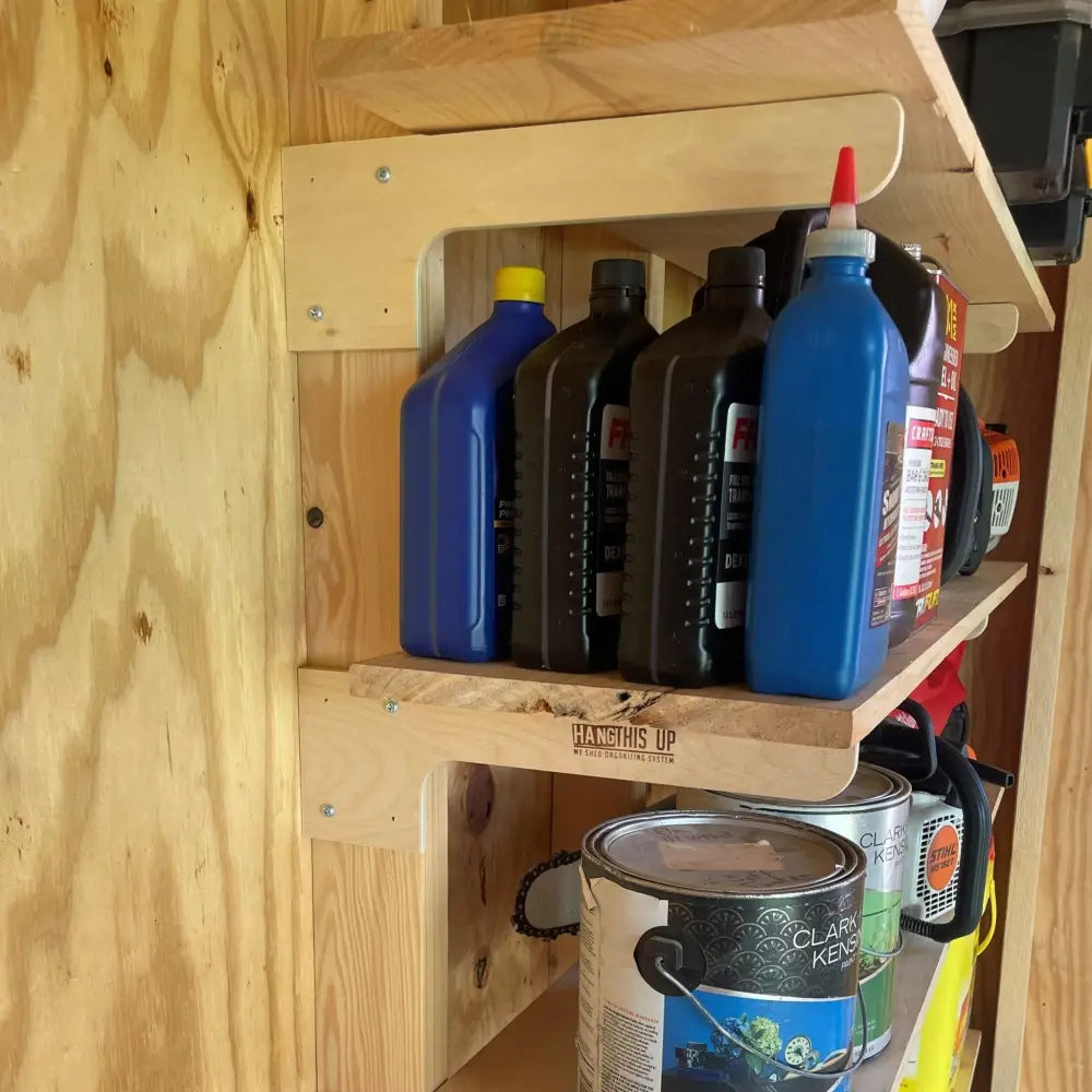 Heavy duty stud mount steel shed shelf brackets kit supporting blue and black plastic oil containers on wooden shelf