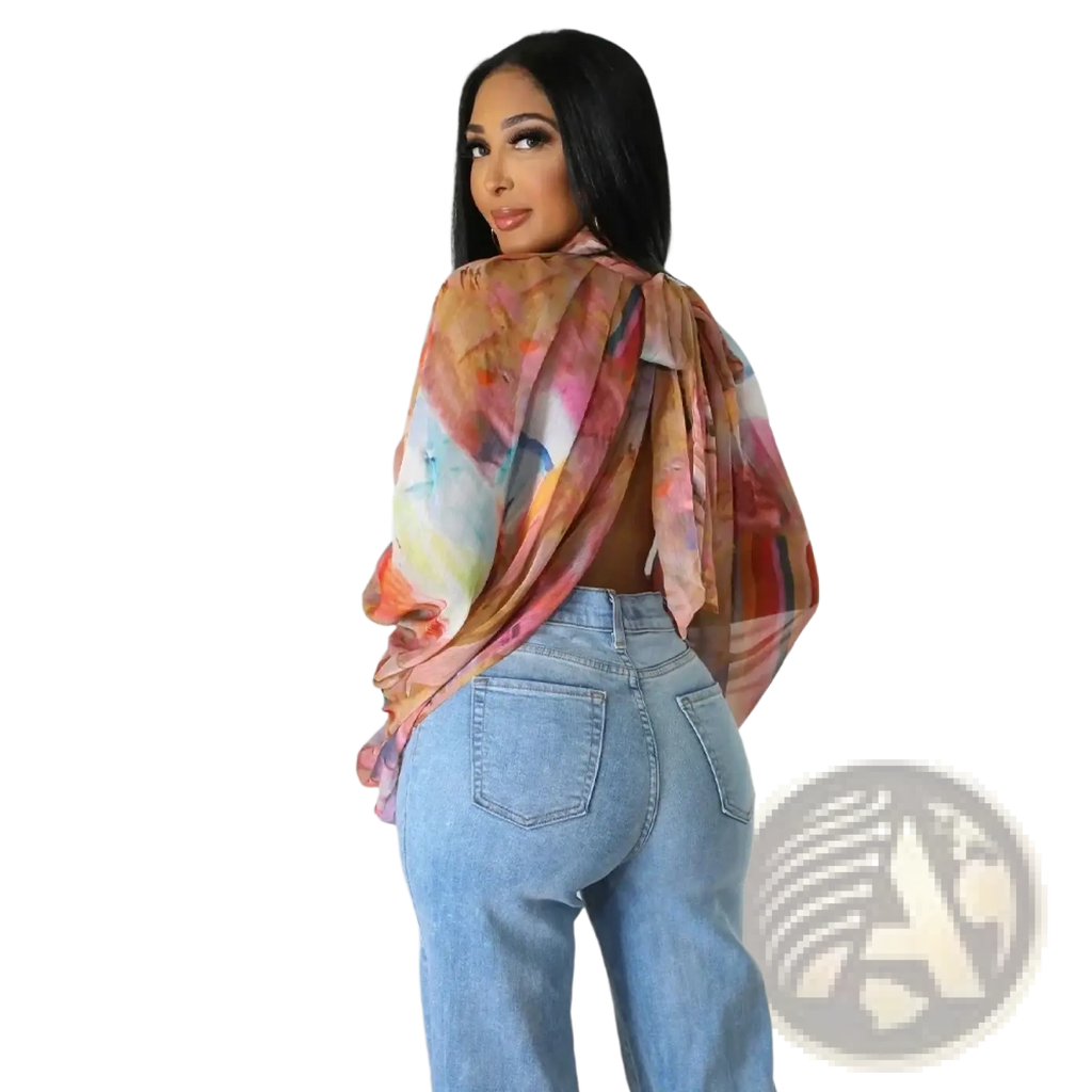A flowing sheer chiffon blouse with a vibrant abstract print in shades of pink orange and blue and a tie neck