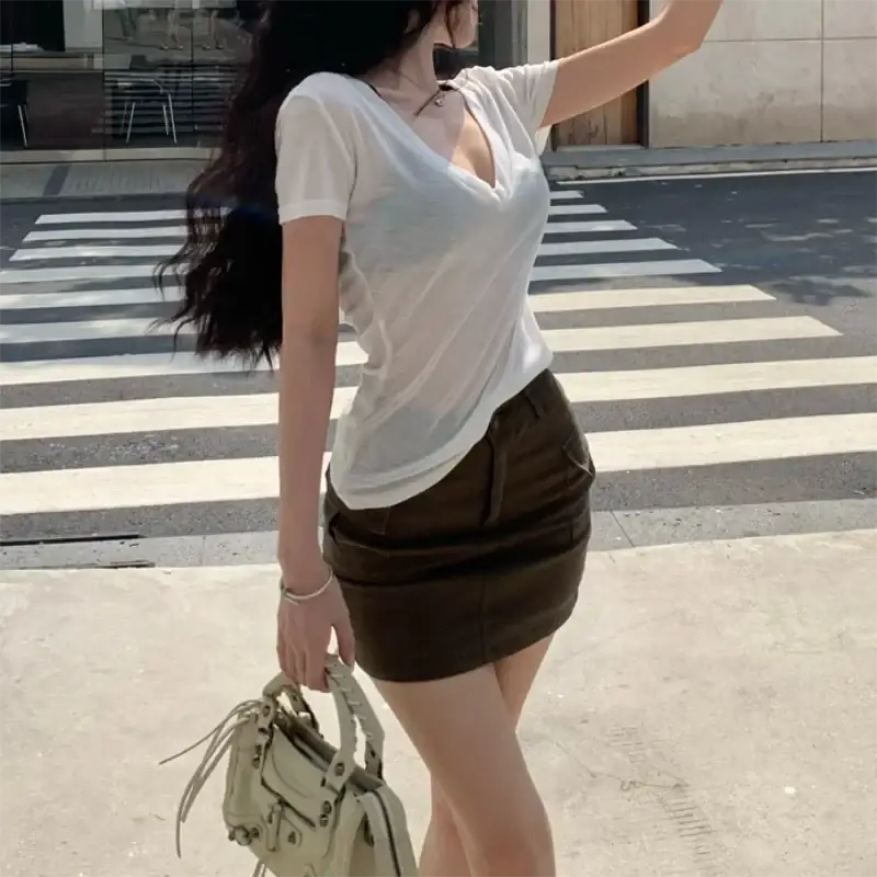 Beige leather handbag with frayed tassel handles and metallic hardware paired with sheer v neck slim short sleeve tee women