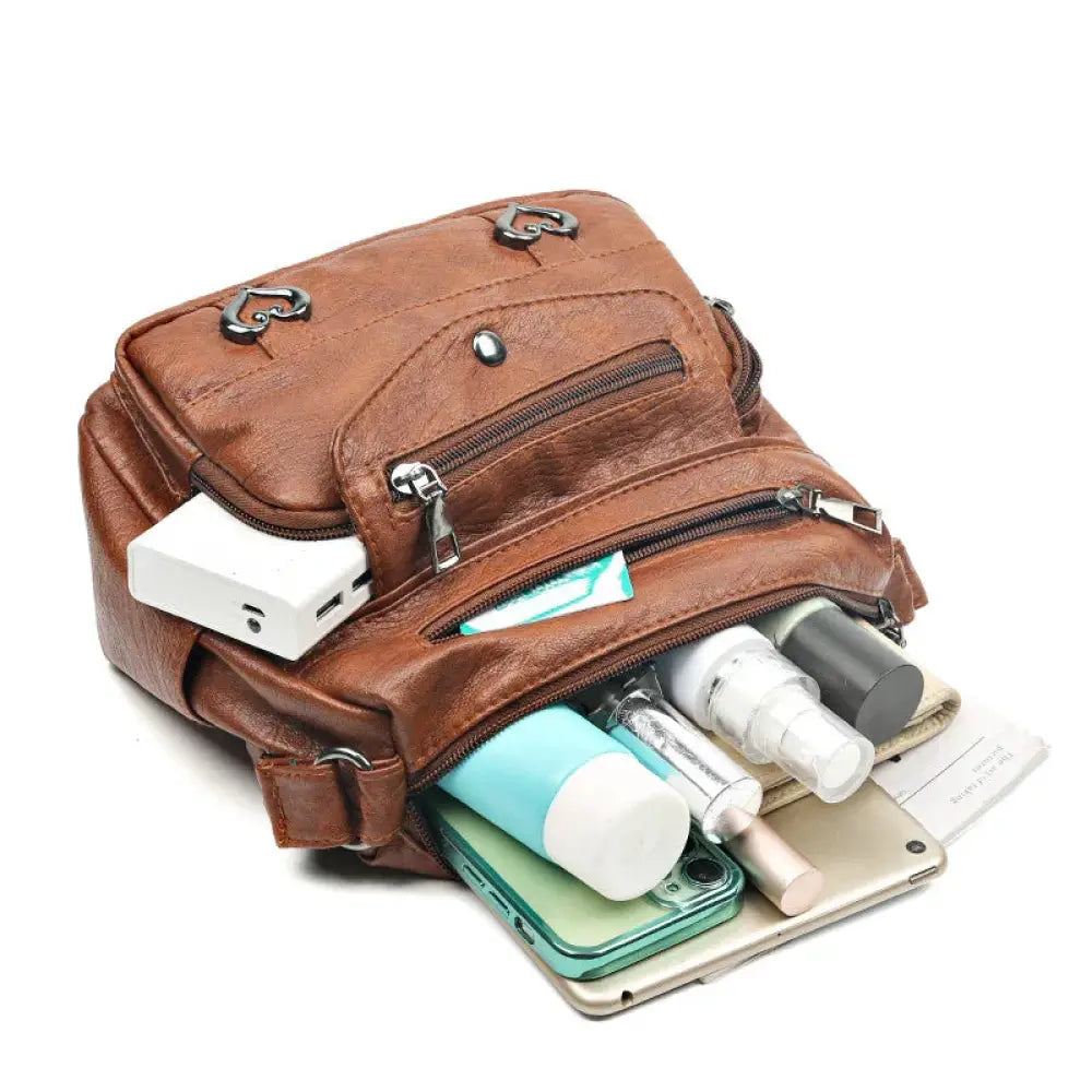Brown leather crossbody bag with multiple zippers and heart shaped metal clasps in women’s multi-pocket design