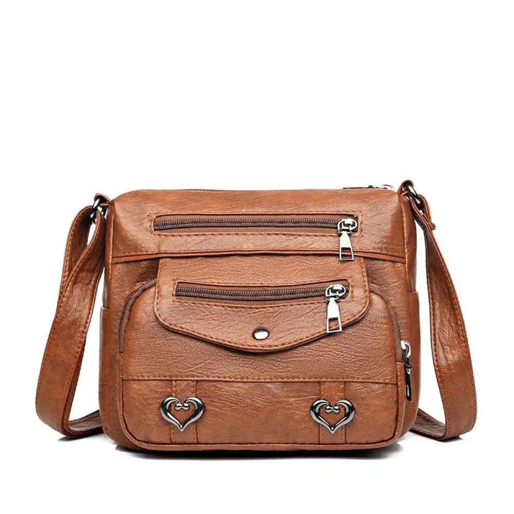 Brown faux leather women’s crossbody bag with silver heart studs and multiple zippers for multi-pocket storage
