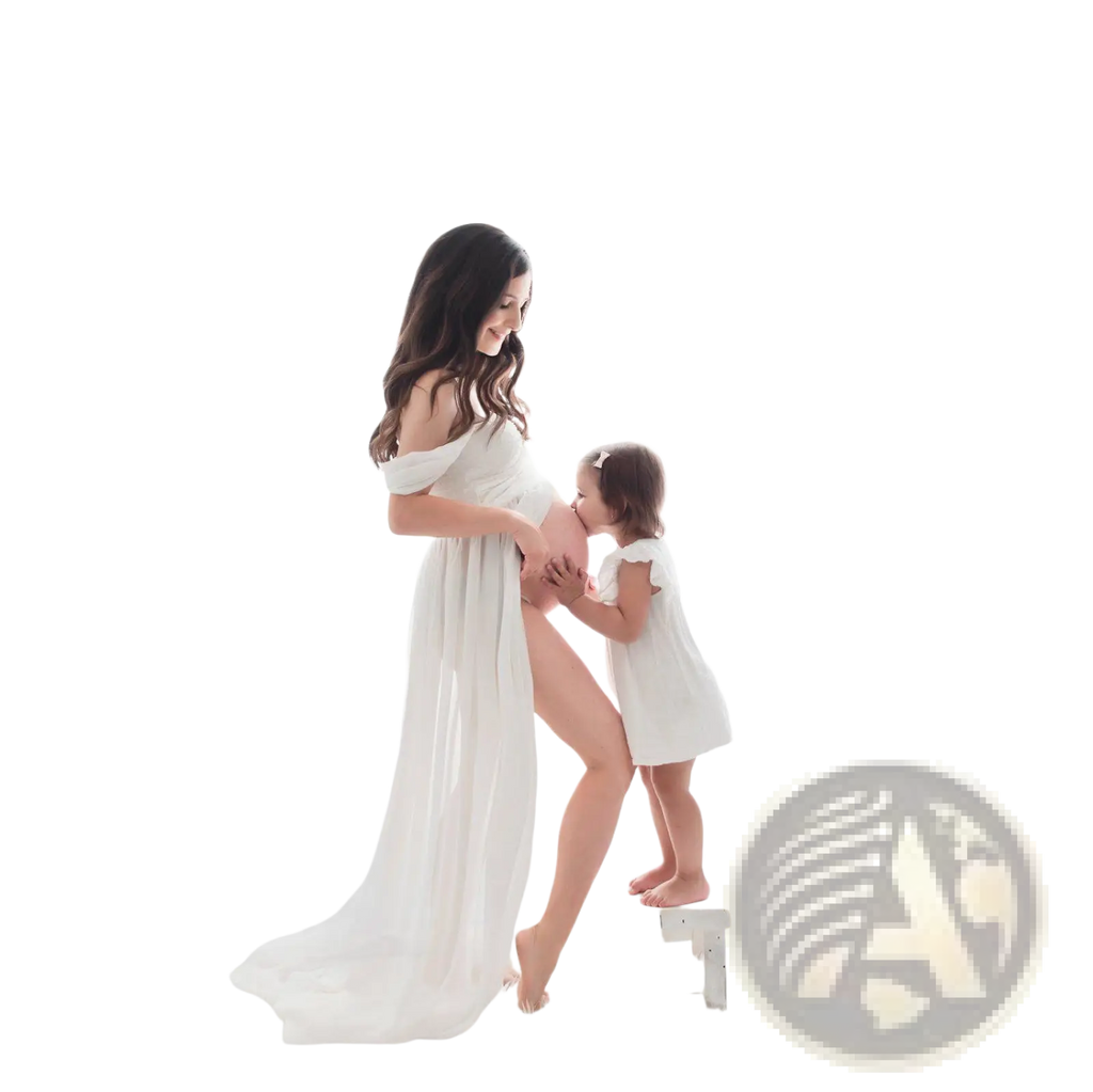 A flowing white chiffon maternity gown with off the shoulder sleeves and a soft draped silhouette for photoshoots