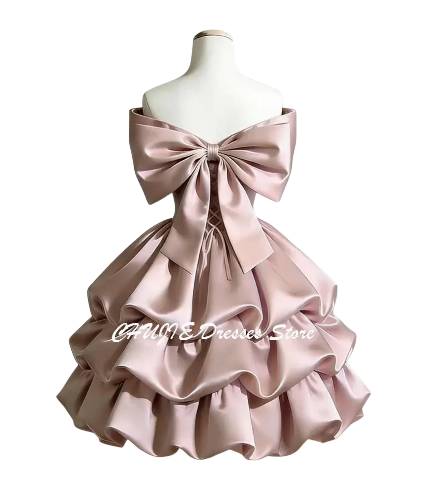 A blush pink satin off-shoulder tiered graduation dress with a large bow at the back shown from the back side