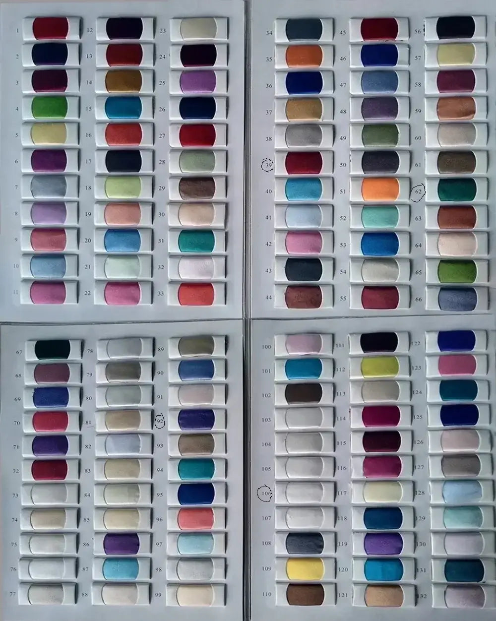 A collection of colorful fabric swatches in white trays for satin graduation dress with off-shoulder tiered design