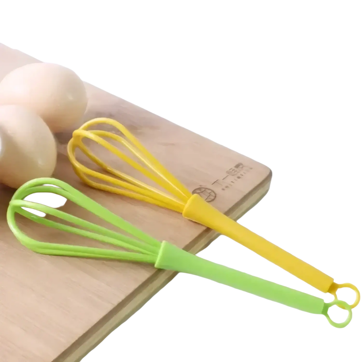 Two colorful silicone egg whisk kitchen hand mixer tools in yellow and lime green resting on a wooden cutting board