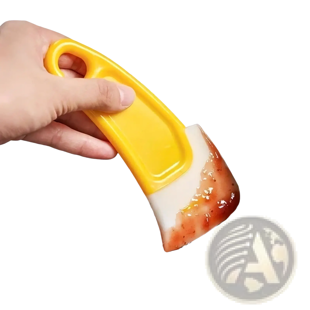 Yellow silicone kitchen pan scraper with white curved blade coated in red sauce for dish cleaning and scraping