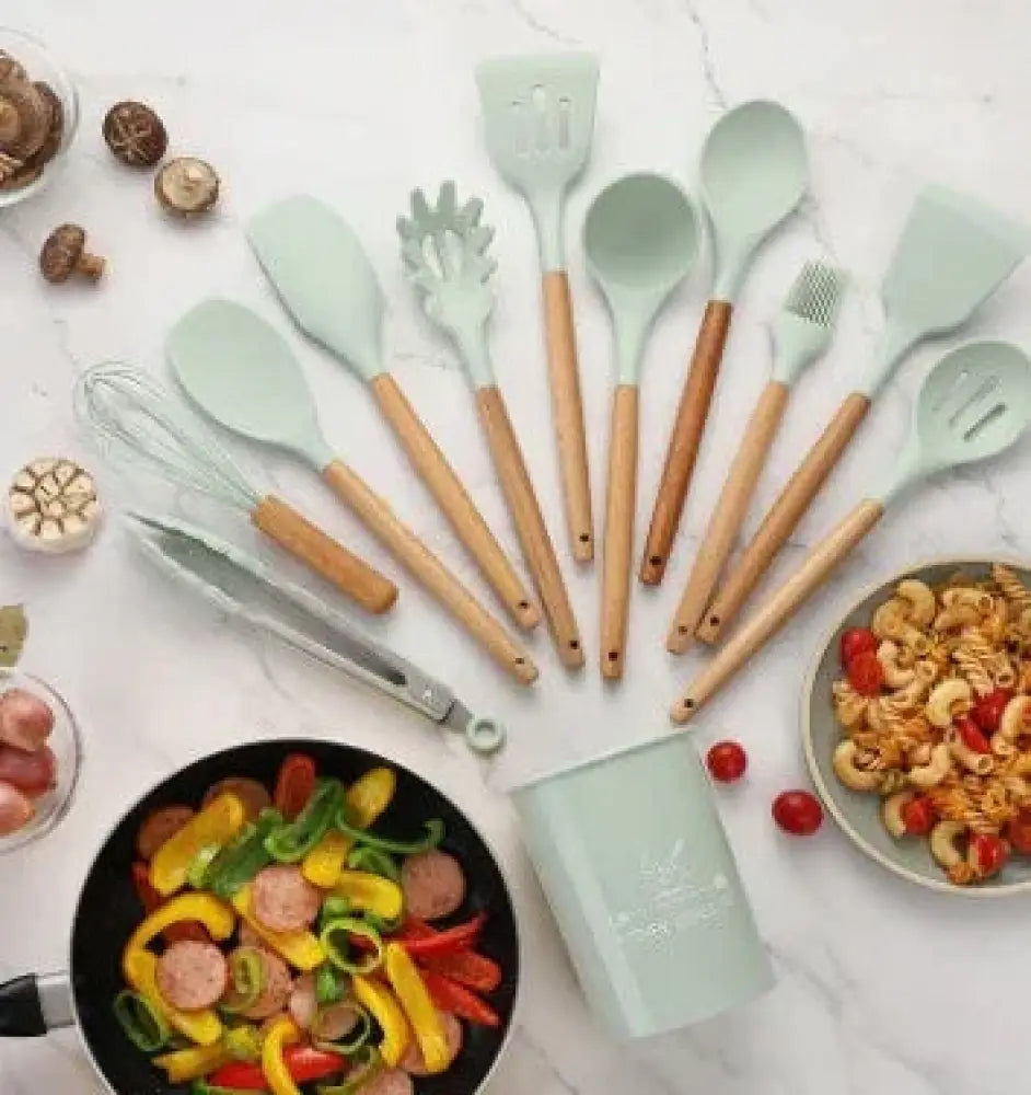 Set of light green silicone and wood heat resistant cooking utensils including spatulas spoons and a whisk