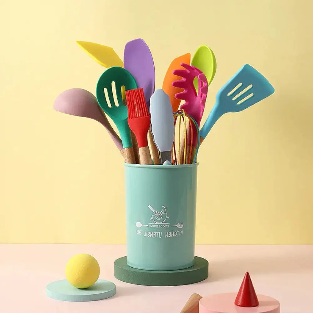 A pastel teal cylindrical utensil holder with a white logo filled with colorful silicone cooking tools and wood handles