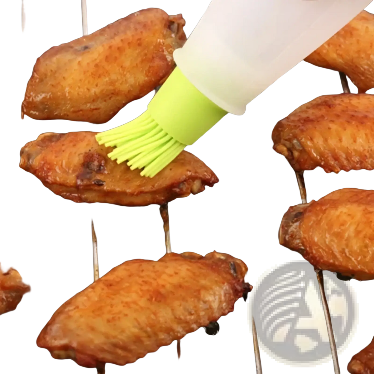 A translucent white silicone oil dispenser brush with bright lime green bristles applying sauce to grilled chicken wings