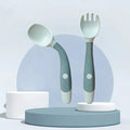 Soft silicone baby spoon and fork self feeding set with soft silicone heads and ergonomic handles in muted gray and white