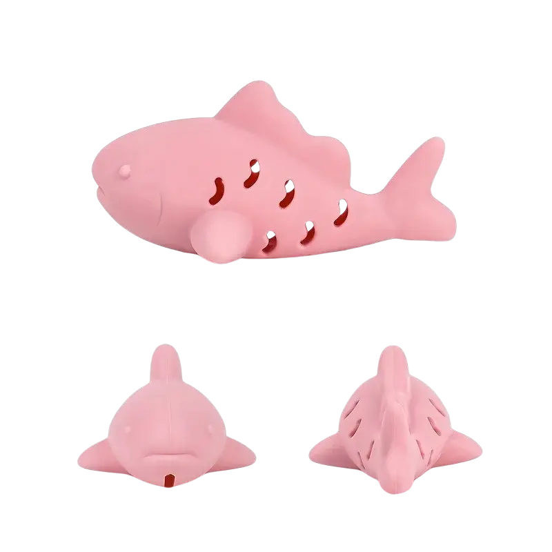 Pink silicone shark-shaped treat dispensing fish toy with perforated body and rounded fins for small pets