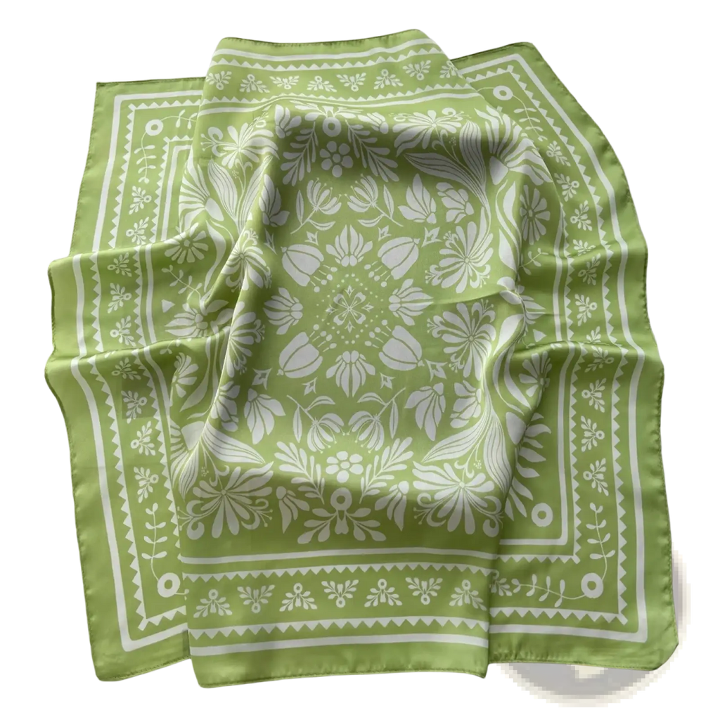 A soft lime green silk square scarf with an intricate white floral botanical pattern and decorative border perfect as a neckerchief or hair band