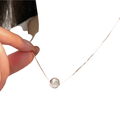 Silver bead pendant necklace featuring a delicate silver chain and a smooth spherical pendant with subtle engravings
