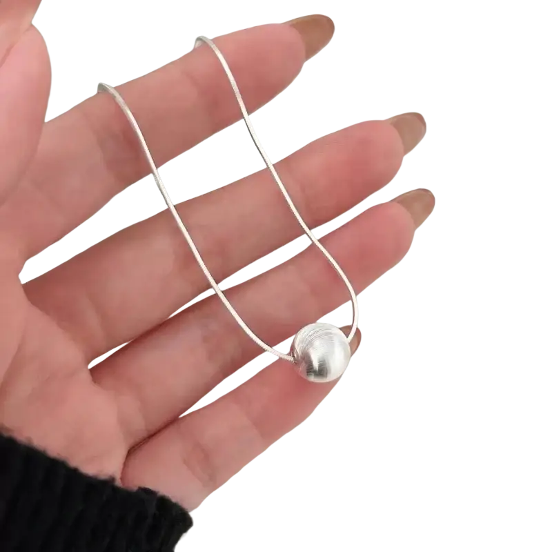 A sleek silver snake chain necklace with a single polished spherical bead pendant minimalist fine jewelry