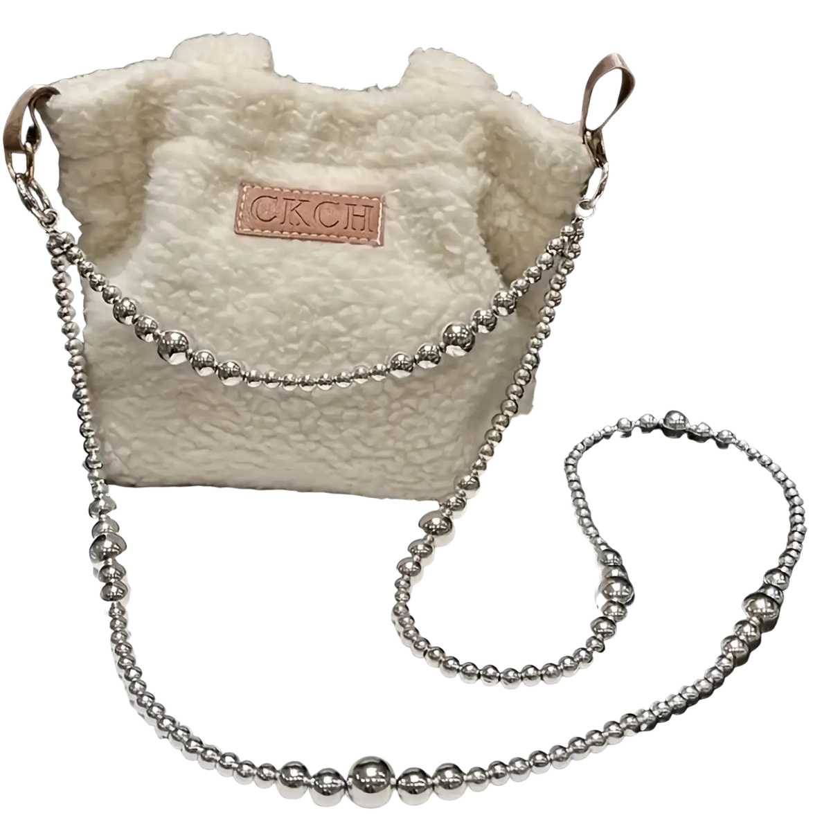 A fluffy white shearling bucket bag with a silver beaded chain strap and brown leather ckch patch