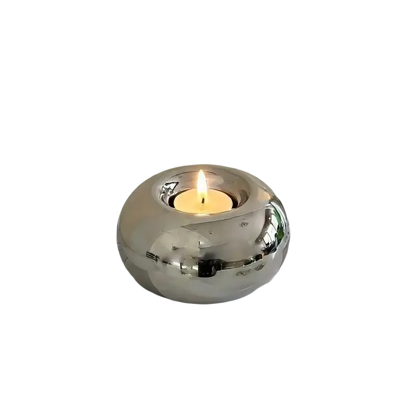Silver ceramic sphere candle holder with shiny finish and lit tea light inside for decorative ambient lighting