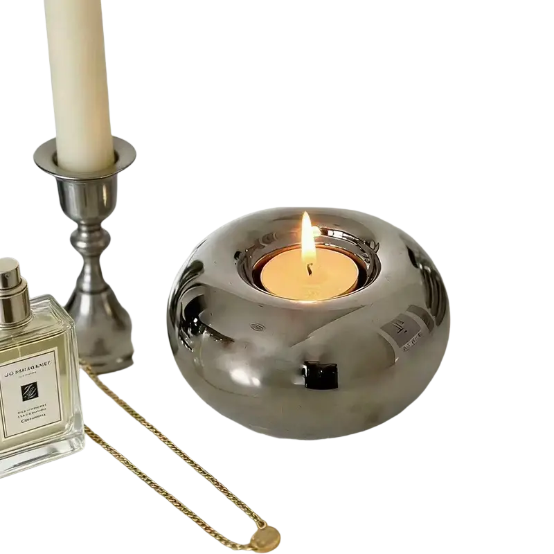 Silver ceramic sphere candle holder with shiny finish and lit tea light inside for elegant ambient lighting