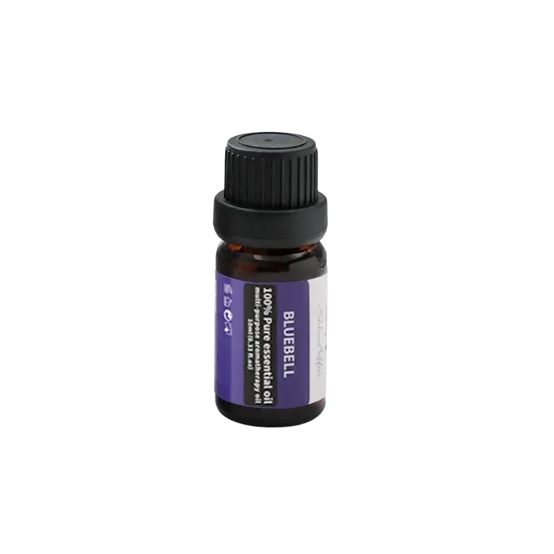 A small amber glass bottle with black ribbed cap and purple bluebell essential oil label beside a silver metallic aromatherapy bowl with black base