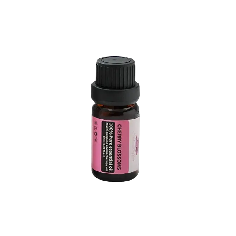 A small amber glass bottle with black ribbed cap and pink cherry blossoms label of pure essential oil inside silver metallic aromatherapy bowl with black base