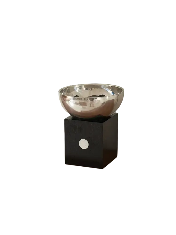 Silver metallic aromatherapy bowl with shiny finish resting on a sleek black cube base with circular white accent