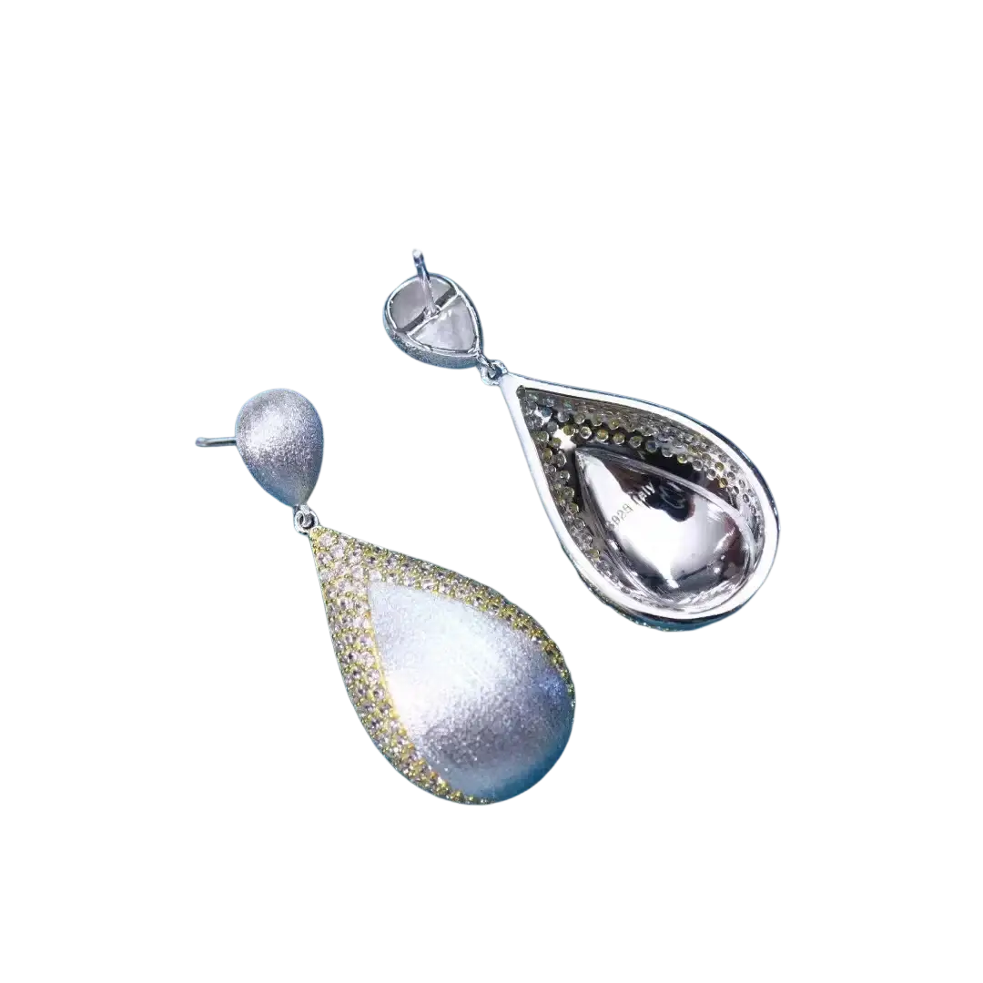 Silver teardrop tassel earrings with shimmering textured silver surface and delicate gold vermeil detailing