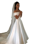 Off the shoulder white satin a line wedding gown with fitted bodice voluminous skirt and attached sheer veil