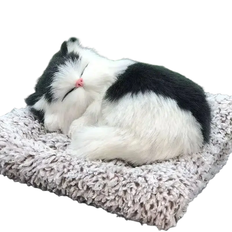 A plush black and white simulated sleeping cat toy with sound curled up on a textured gray cushion with a pink nose