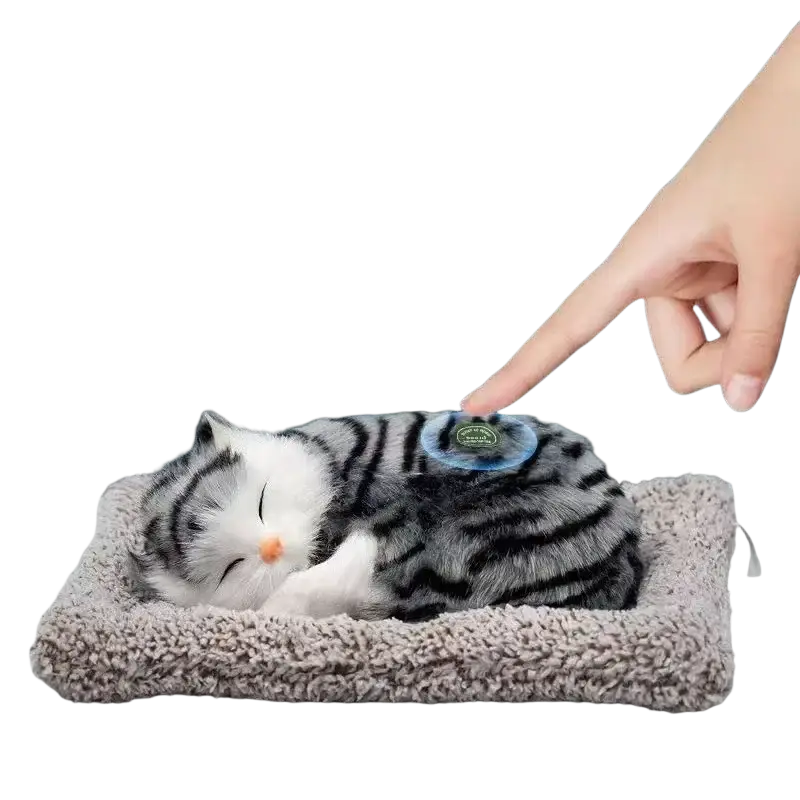 A plush gray and white striped simulated sleeping cat toy with sound rests on a soft textured gray cushion
