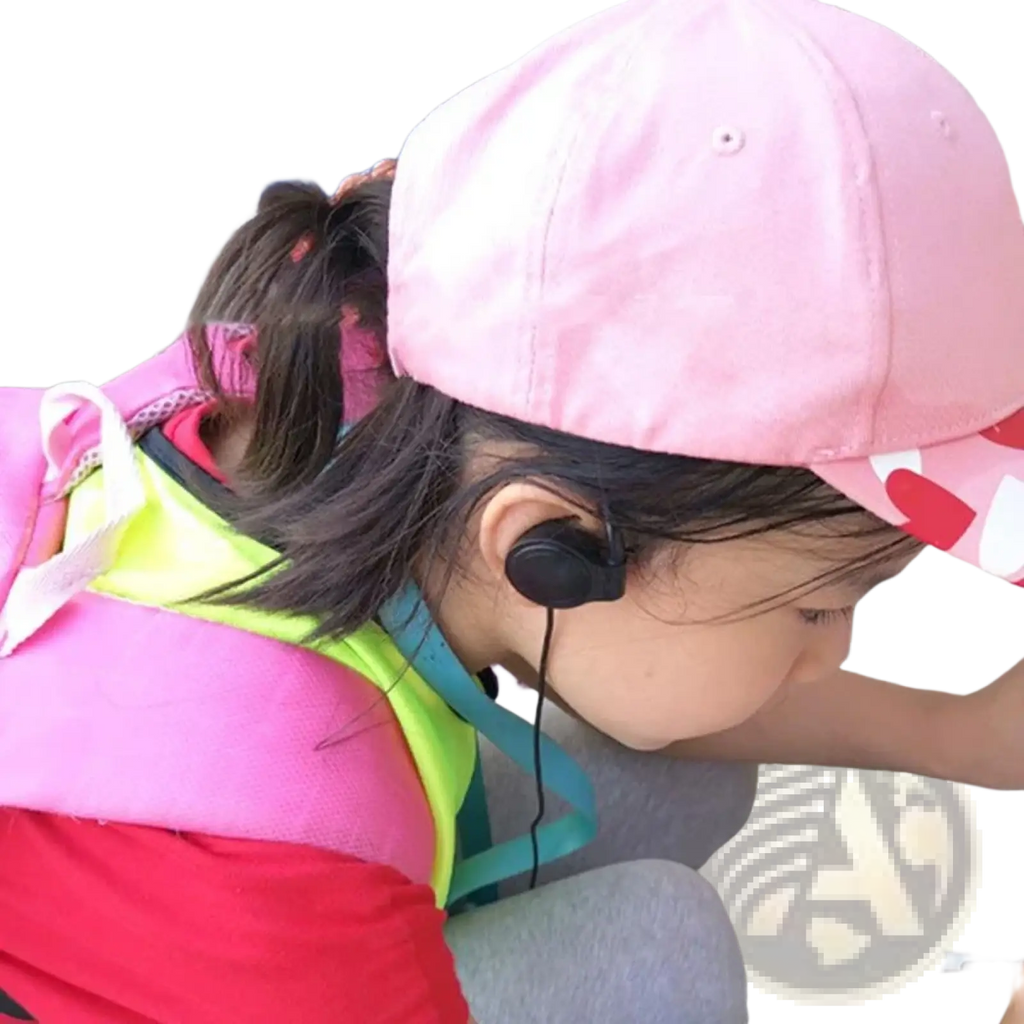 Pink baseball cap with red and white heart pattern alongside single ear hook 3.5mm wired headphone for audio use