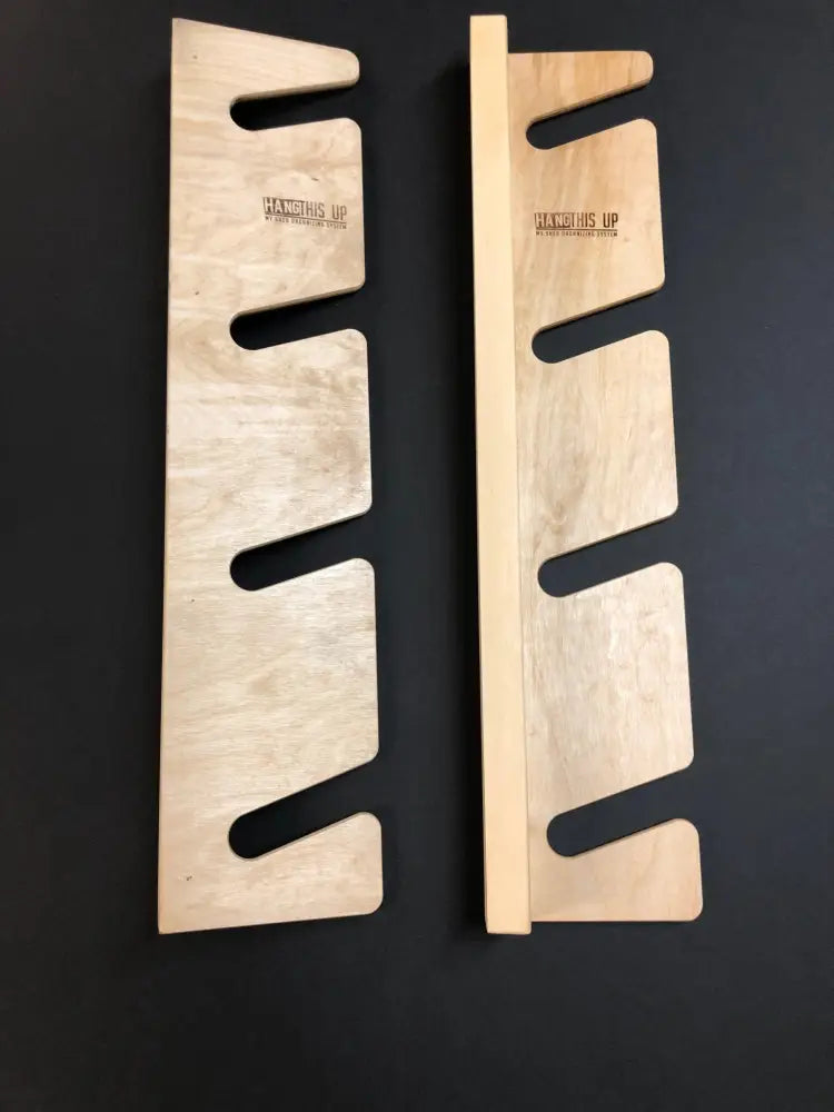 Light-colored wooden wall-mounted knife rack with cutout slots and hang this up branding for vertical storage