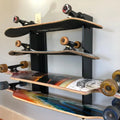 Black metal wall-mounted multi deck vertical skateboard and snowboard rack holding five skateboards with varied designs
