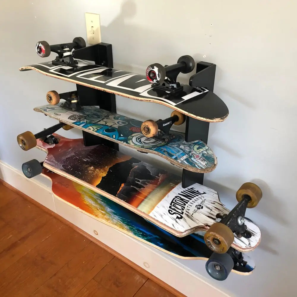 Multi deck vertical skateboard and snowboard wall rack holding three longboards with colorful graphic wooden wheels