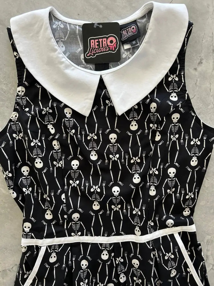 Black sleeveless cotton a-line dress with white skeleton print and contrasting white peter pan collar with pockets