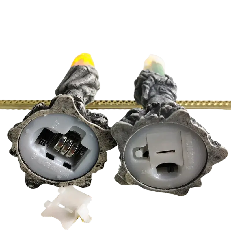 Two gray textured skeleton hand led candle holders with glowing flames and battery compartments for happy halloween party