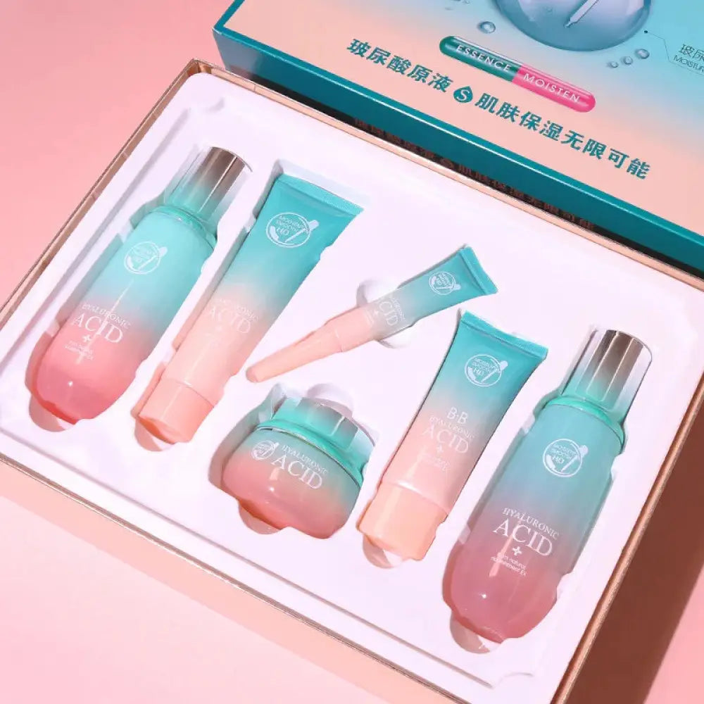 A gradient pink to teal hyaluronic acid hydrating skincare gift set with five metallic capped bottles and tubes in a box