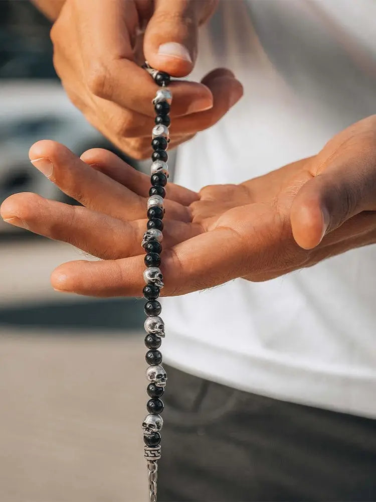 Black obsidian and silver skull beaded bracelet with alternating polished black and silver skull beads on a wrist