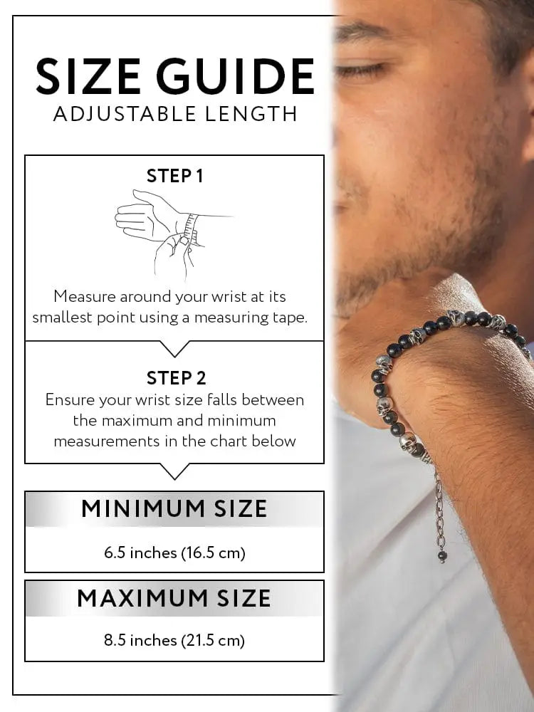 A man wearing a black obsidian and silver beaded bracelet with skull charms on the wrist