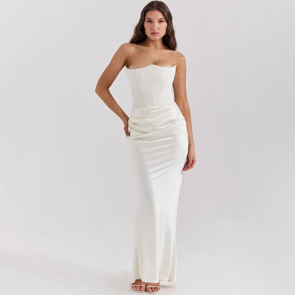 A sleek white satin strapless backless mermaid evening gown with a fitted bodice and flowing skirt